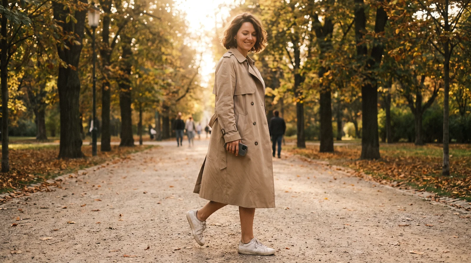 Žena kolem pětačtyřiceti jde na procházku podzimním parkem po obědě